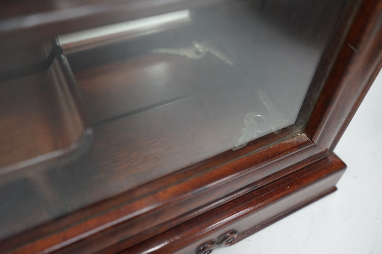 A narrow Chinese hardwood display cabinet, fitted with decorative shaped hardwood shelving, 82.5cm high x 53cm wide at base x 10.5cm deep at base. Condition - marks to wood when cello tape has been, other wise good